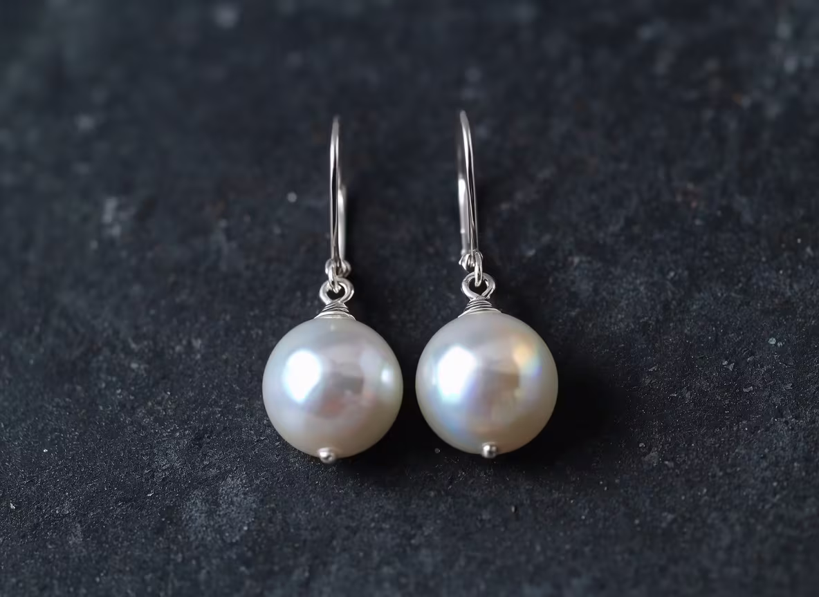 Pair of freshwater pearl drop earrings on a dark slate surface